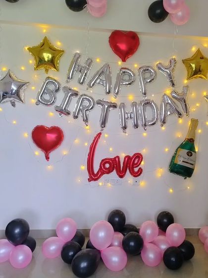 A modern and chic birthday wall decoration with foil balloons and fairy lights.