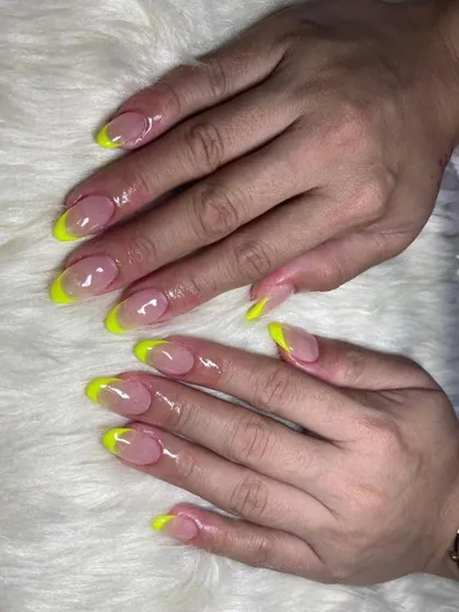 Neon yellow French tips on long almond nails. This electrifying color is perfect for summer, vacations, or whenever you're feeling bold.