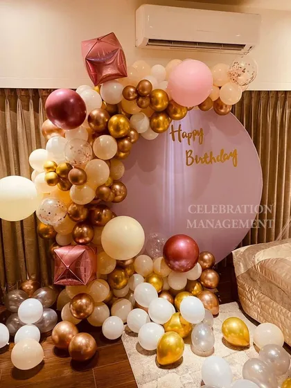 This beautiful pastel balloon arch is set against a circular lavender backdrop. The mix of white, gold, pink, and cream balloons creates a soft and dreamy photo spot.