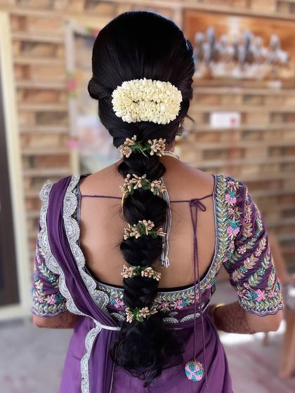 A simple yet elegant reception hairstyle. This bubble braid is adorned with delicate floral accessories and a traditional jasmine veni at the base.