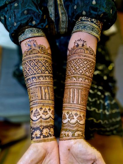 The back of the hands, showing a continuous traditional pattern with peacocks, elephants, and geometric jaali work.