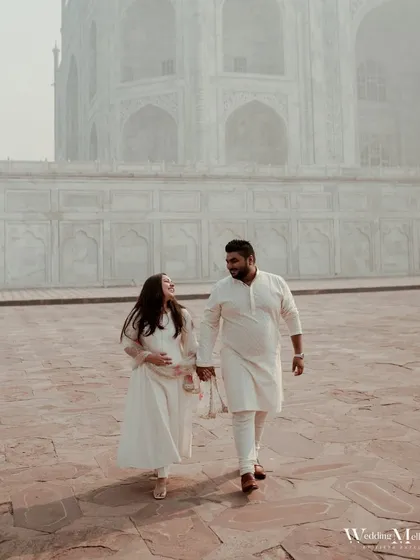 A beautiful shot of the couple walking hand-in-hand at the Taj Mahal. The soft, warm tones and the grandeur of the location make this a truly romantic and iconic pre-wedding photograph.