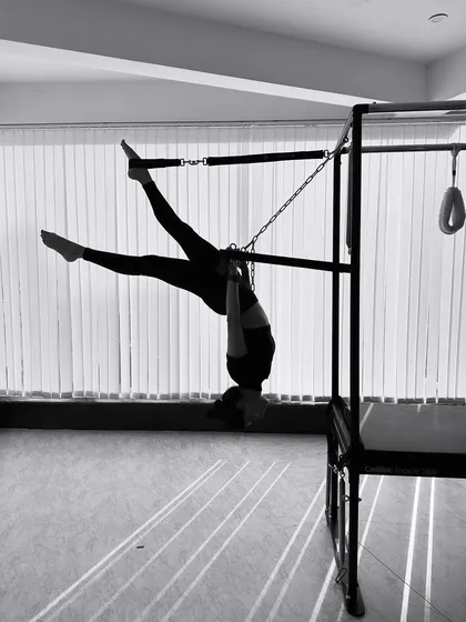 The play of light and shadow in this black and white image highlights the strength required for this inverted hanging pose.
