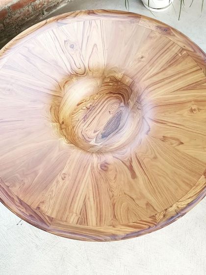 A top-down view of the finished sculptural table, showcasing the intricate wood grain pattern and the unique concave detail at the center. The perfect finish is a testament to our team's skill.