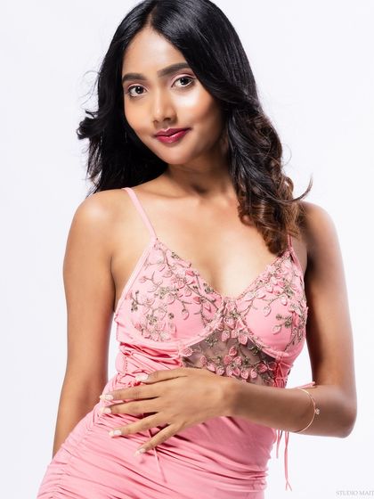 A three-quarter shot of the model in a pink dress, with a gentle and confident pose.