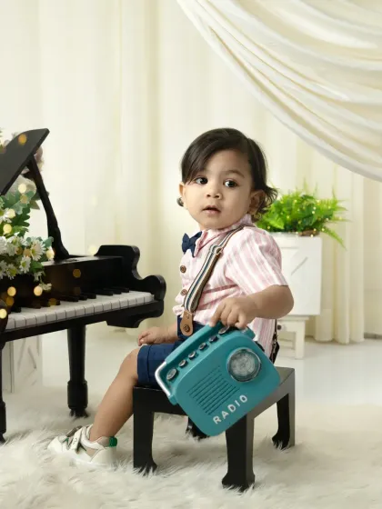 A little gentleman and his radio. This vintage-themed milestone session features a miniature piano and classic props for a timeless and stylish look.