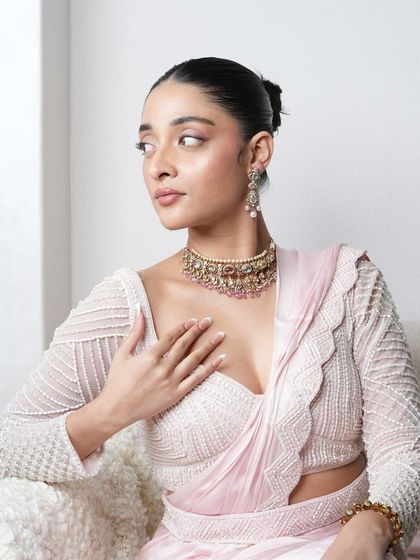 A model wearing the pastel Navratan pearl choker set, paired with a delicate pink saree for an elegant, festive look.