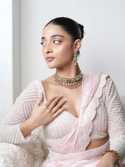 A model wearing the pastel Navratan pearl choker set, paired with a delicate pink saree for an elegant, festive look.