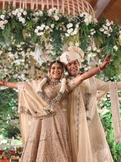 A triumphant and joyful pose from the couple on their wedding stage, celebrating their union with arms wide open.