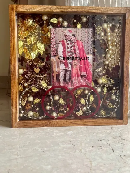 Here is a detailed look at a teakwood frame preserving a couple's varmala and wedding bangles. The combination of red bangles, flowers, and golden elements creates a rich and vibrant display.