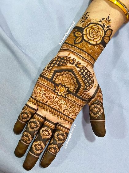 An elegant design featuring a mix of floral and traditional motifs. A large rose on the wrist is complemented by a peacock and lotus on the hand.