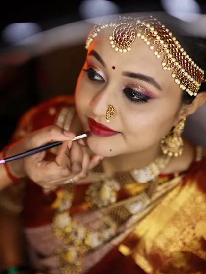 Applying the final touch of lipstick. This close up shows the precision and detail that goes into every look.