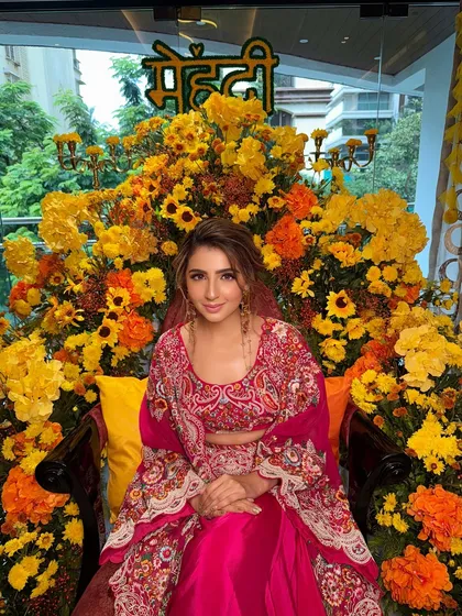 Surrounded by a throne of marigolds, this bride is the epitome of Mehendi joy. Her fun and festive hairstyle perfectly complements the colorful and celebratory atmosphere.