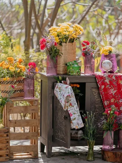 A corner vignette filled with rustic crates, colorful vases, and overflowing floral arrangements, creating a rich, layered look.