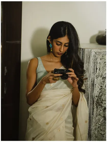 A meta-narrative of a photographer being photographed. This indoor environmental portrait uses props and soft lighting to tell a story about creativity.