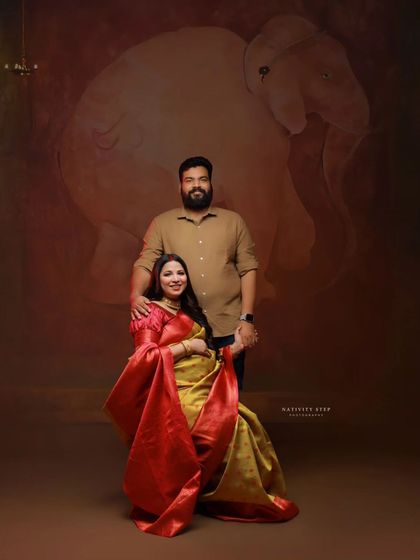 A lovely family portrait with the couple in traditional attire. The warm tones of the saree and the studio background create a feeling of togetherness.