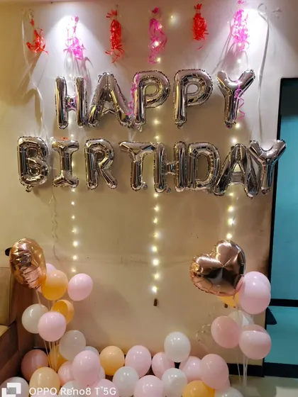 A simple and sweet birthday setup at home, with "Happy Birthday" foil balloons and pastel-colored balloons on the floor.