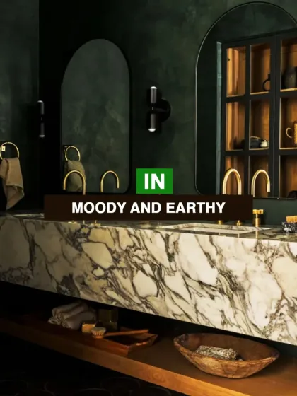 Moody and earthy tones are 'in'. This bathroom showcases a bold design with dark green walls and a heavily veined marble countertop, creating a rich and sophisticated look.