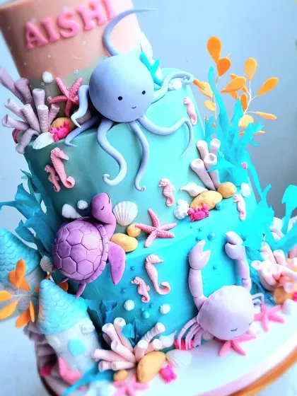 A vibrant, multi-tiered underwater cake. This design is packed with sculpted sea creatures like an octopus, turtle, crab, and whale, all made from fondant.