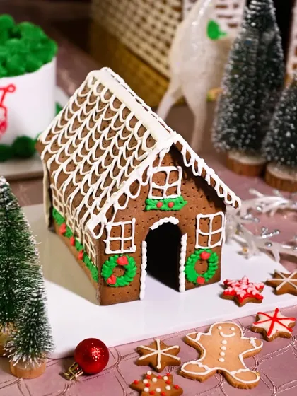 A classic gingerbread house decorated with icing, set in a miniature winter wonderland with cookie trees. This image is the epitome of traditional Christmas baking and holiday cheer.