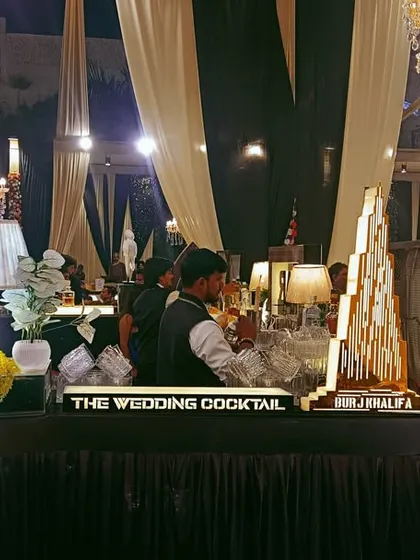A classic and elegant bar setup with a custom light-up 'BAR' sign, perfect for a traditional wedding reception with grand chandeliers and decor.