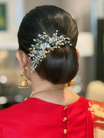 A close-up of a perfectly sculpted low bun, accented with a delicate, jeweled hairpiece. This sleek and sophisticated updo is a versatile choice for modern brides or for adding a touch of grace to any formal event outfit.