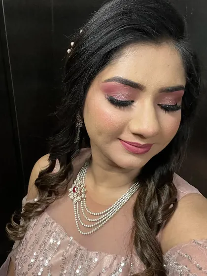 A close-up of the sparkling pink glitter eyeshadow. This look is paired with a side-parted hairstyle with soft curls that frame the face.