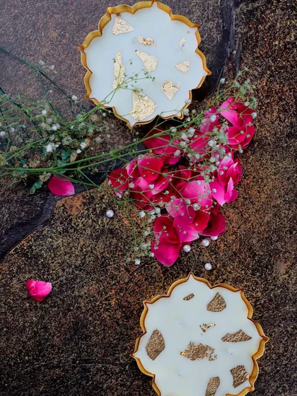 An aerial view of two mini gold Urli candles, styled with rose petals and baby's breath, showcasing their decorative potential.
