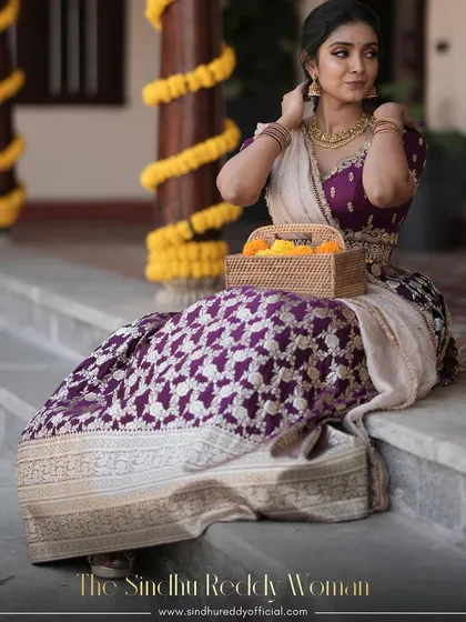 A beautiful seated portrait of our client in the purple brocade lehenga, holding a basket of festive flowers.
