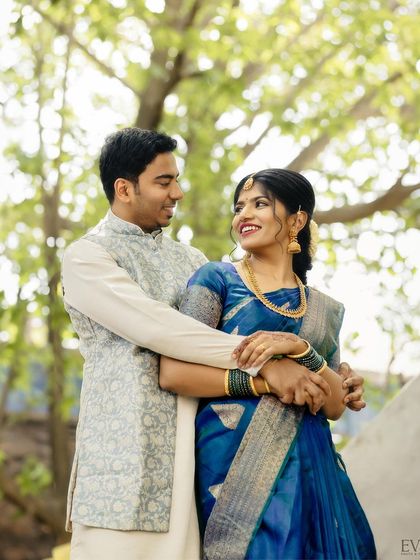 The couple shares a joyful look in this beautiful outdoor engagement portrait, surrounded by lush greenery.