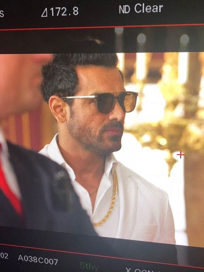 A monitor shot of John Abraham during a film shoot. His look here, with the open white shirt and gold chain, was crafted to build his character's persona.