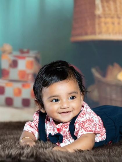 This little one is all smiles during his tummy time session on a soft brown rug.