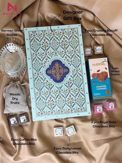 A truly royal hamper. This set includes a designer gift box, a German silver basket, masala dry fruits in a pouch, assorted chocolate bites, and almond cookies. It’s a luxurious gift meant to impress.