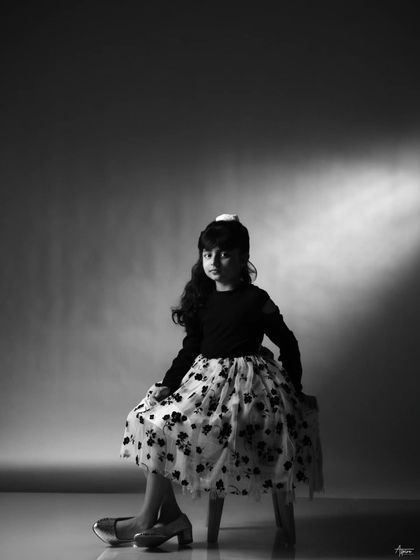 A classic black and white portrait using a single spotlight. This technique creates a timeless, cinematic look that emphasizes her poise and elegance, even at a young age.