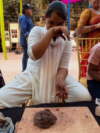 Sometimes the process is messy, and that is part of the joy. A participant laughs as she works with the wet clay during our outdoor festival workshop.