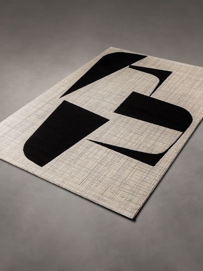 A bold, minimalist rug with a black abstract design on a light, textured background. It's a perfect choice for a modern, high-contrast interior.
