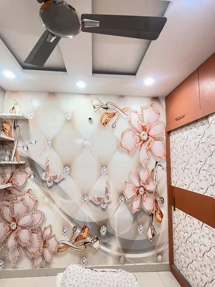 A close-up of a bedroom wall with a 3D wallpaper of pink flowers and butterflies on a quilted background, adding texture and glamour.