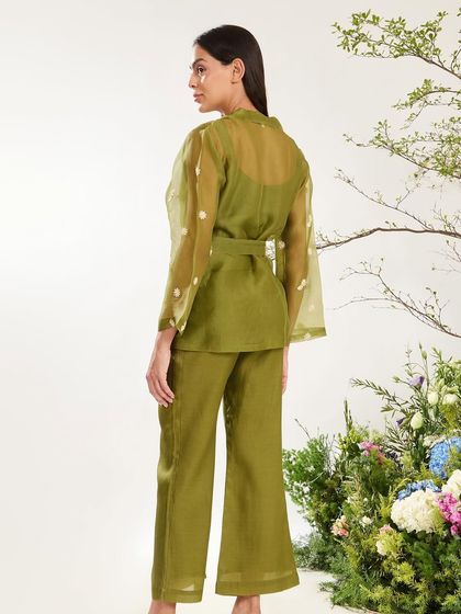 Fresh hues, floral mood. A model wears an olive green co-ord set with a sheer organza jacket featuring delicate white floral embroidery.
