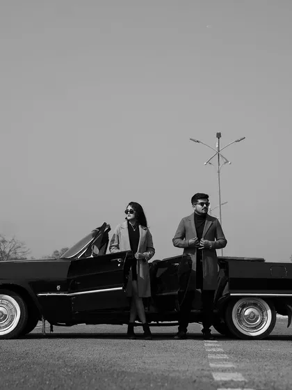 A wide, atmospheric shot of the couple with their vintage convertible. This black and white photo has a classic, old-Hollywood feel, perfect for a themed pre-wedding album.
