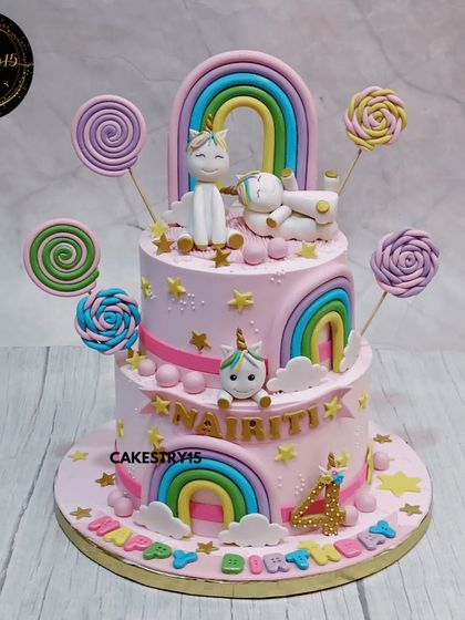 A vibrant two-tier Candyland unicorn cake. This choco-vanilla cake is a burst of color, decorated with fondant unicorns, rainbows, and an assortment of candy lollipops for a fun and sweet celebration.