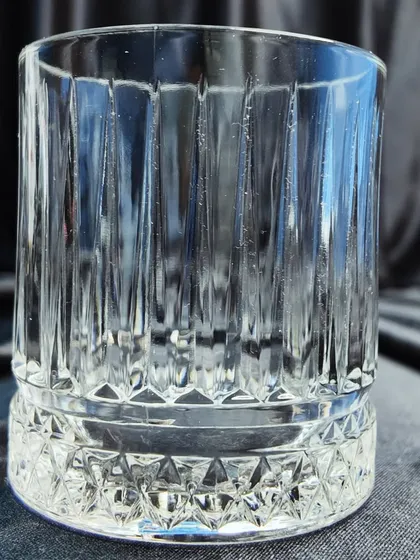 A crystal-cut whiskey tumbler, also known as an Old Fashioned glass. This is the proper glassware for serving neat spirits or short cocktails.
