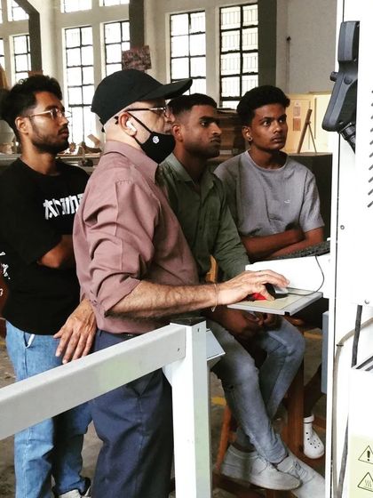 An instructor demonstrates the setup and operation of a CNC machine to a group of attentive students. This training covers how to translate a digital file into a machine-operated cutting process.