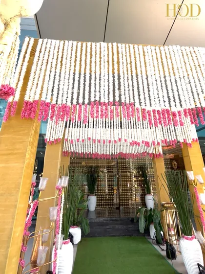 A view from inside the entrance arch, looking out through a curtain of white and pink flowers, creating a beautiful and fragrant welcome.