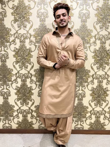 A full-length view of the beige Pathani suit, showing the traditional salwar-style trousers. The intricate embroidery on the cuffs and hem adds a touch of bespoke luxury.