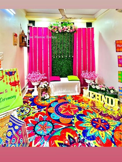 A wide view of the entire Mehendi/Dholki setup, showing how I can transform a room into a vibrant celebration space with a colorful carpet, backdrop, and props.