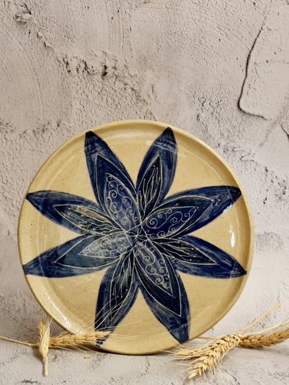 This handmade and hand-painted ceramic plate features a large, intricate blue floral design. It's a unique and artistic present for you or your loved ones.