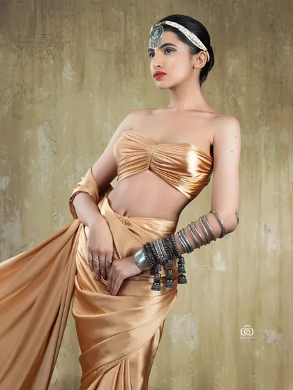 A full-length shot of a model in a flowing golden outfit, styled with traditional Indian jewelry. The movement in the fabric adds a dynamic element to this Indo-western concept.