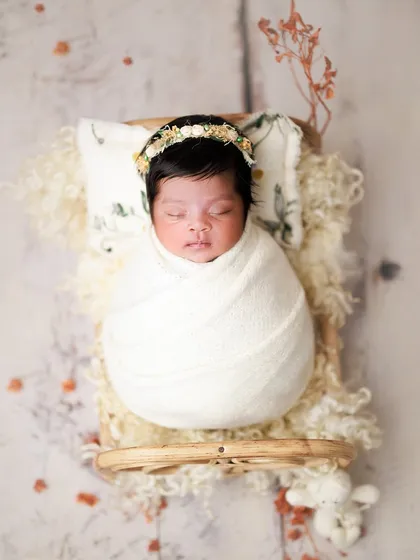 Cradled in white serenity. This classic all-white setup on a miniature bed is timeless. The delicate floral headband adds just a touch of nature.