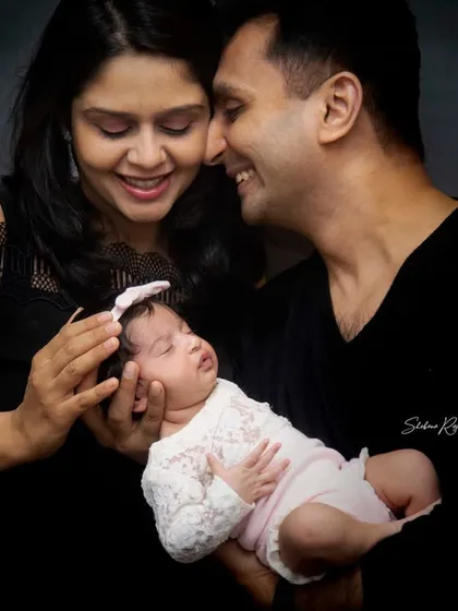 A candid moment from a newborn family photoshoot. The parents share a loving look while holding their sleeping baby, a perfect example of the gentle, emotional moments I aim to capture.
