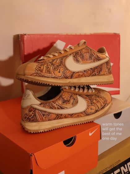 Here's a closer look at the travel-themed doodle on the coffee-dyed Nike Cortez. The warm, monochrome tones give it a cohesive and artistic feel, with every inch covered in unique illustrations.